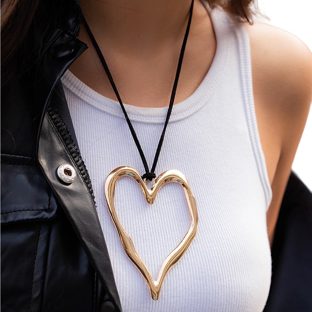 Large gold-tone Freeform heart necklace on a black faux leather cord.